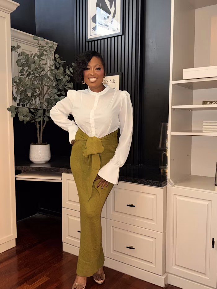 Dr. Mia Young standing in her office in a white blouse and olive skirt
